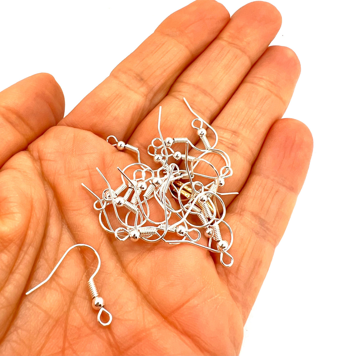 Hand holding a collection of silver earring hooks on a white background