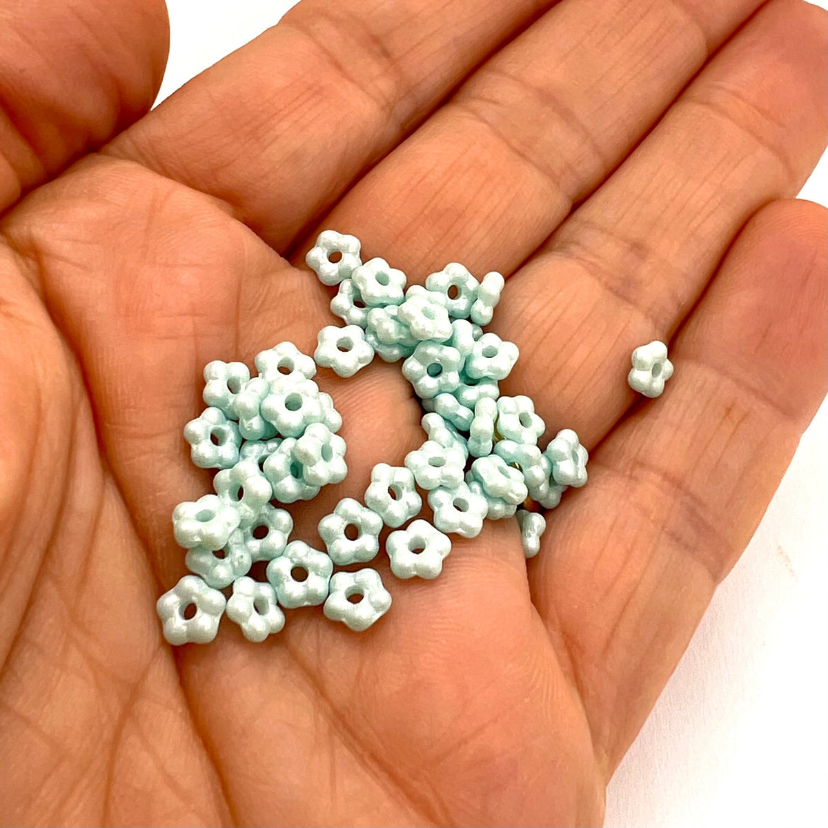 Small light blue flower beads on a hand